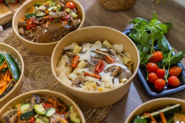 Kremalı rigatoni, sotelenmiş mantar, vişneli domates ve ahşap masadaki parmesanlı gübre kasesinin yakın çekimi. Yanında taze fesleğen ve domates. Yatay resim.