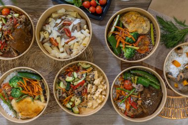 Ahşap bir yüzeyde pirinç, makarna, sebze ve soslu yedi renkli yemek kasesinin genel manzarası. Taze malzemeler ve kırsal malzemeler de dahil. Yatay resim, düz çizgi.