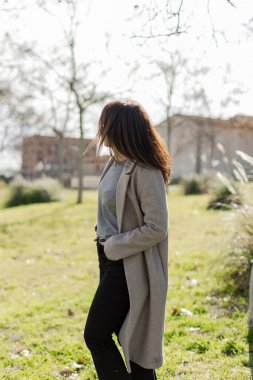 Kadın elleri ceplerinde, saçları rüzgarda uçuşurken dışarıda duruyor. Sakin, özgür, düşünceli hissettiriyor. Yaşam tarzı, sağlık, yaratıcılık temaları için harika. Dikey, kopyala.