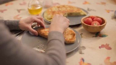 Kadın ellerinin geleneksel Katalan pa amb domatesli tostu hazırlarken, İspanyol omleti, zeytinyağı şişesi ve domatesler arka planda oturuyor. Tanınmaz halde. Yatay, 4K