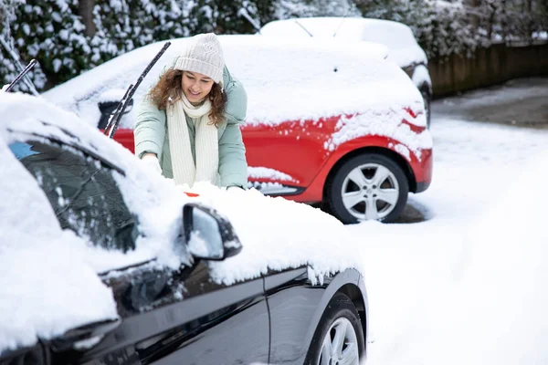 若いです女性クリーニング彼女の車から雪で背中 — ストック写真