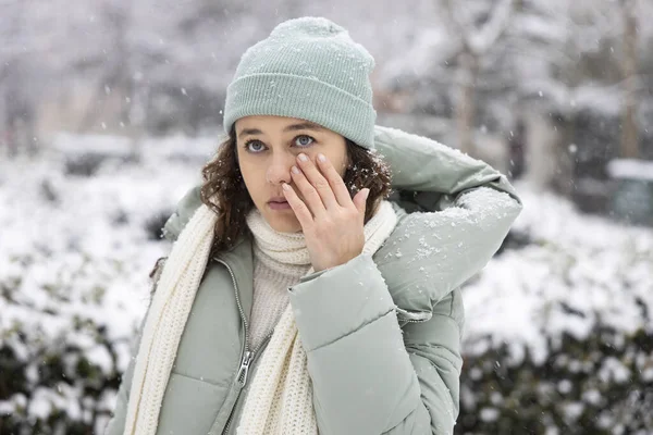 Young woman having itching eyes health problem. Sick woman in winter snow touching her sensitive eye