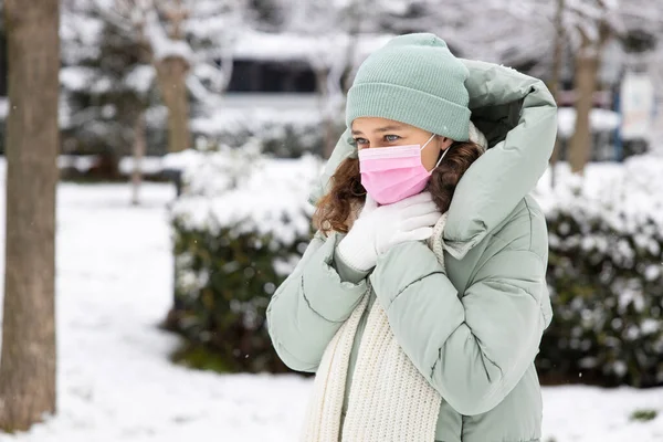 Young woman with throat pain walking the street in a cold winter da