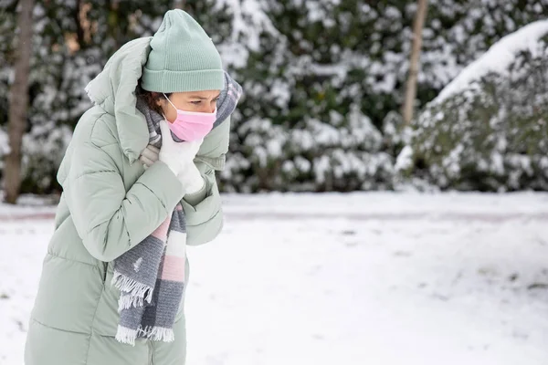 Young woman with throat pain walking the street in a cold winter da