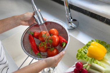 Woman washing vegetables on kitchen counte