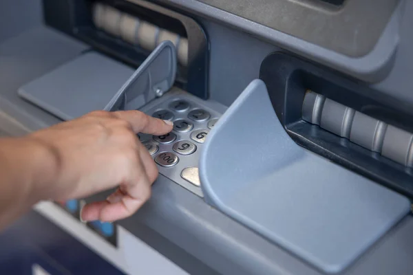 Woman hand entering pin code in ATM machine to withdraw cash