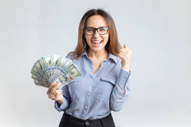 Portrait of a cheerful young businesswoman holding money banknotes and celebrating to succes
