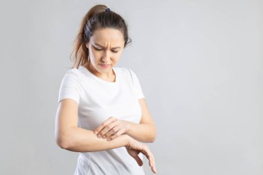 Young woman scratching her itchy arm. Skin problems concept