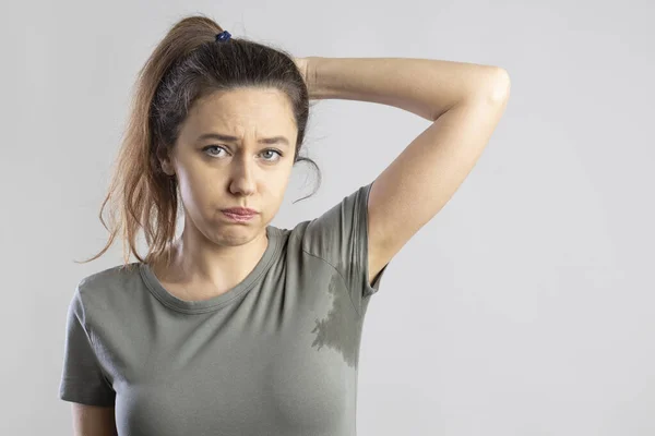 Excessive sweating problems. Young woman with her arm raised with her armpits sweat