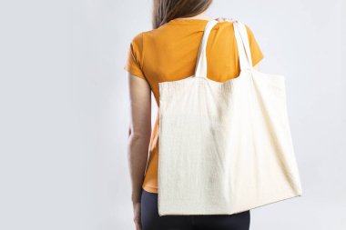 Young woman holding eco-friendly shopping bag on white background