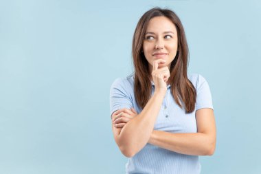 Young woman thinking creating plan over bright blue teal turquoise background
