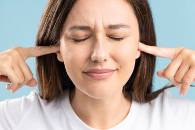 Young woman covering ears with her fingers, not wanting to hear