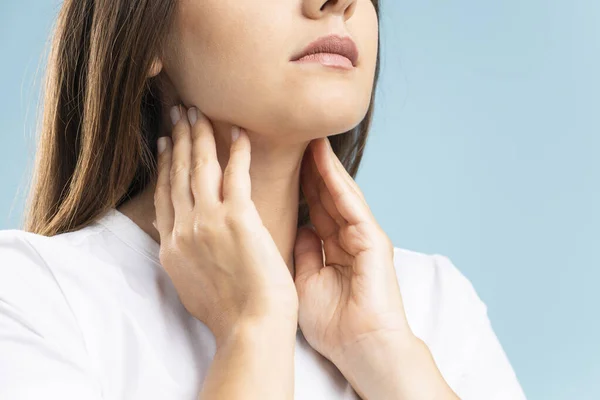 stock image Sore throat, woman with pain in neck, blue background, studio shot