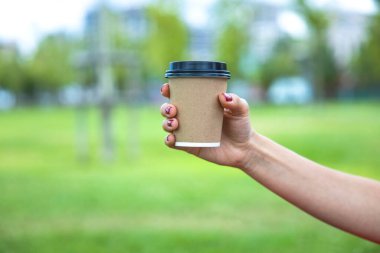 Close up of young woman holding a cup of takeaway coffee cu