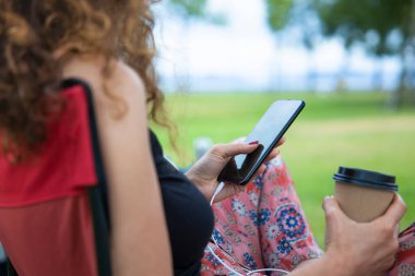 Close-up image of woman looking the music list and drinking coffee in park