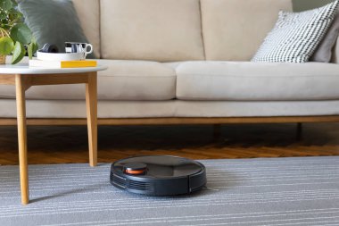 Robot vacuum cleaner on the carpet. Cleaning in living room at home