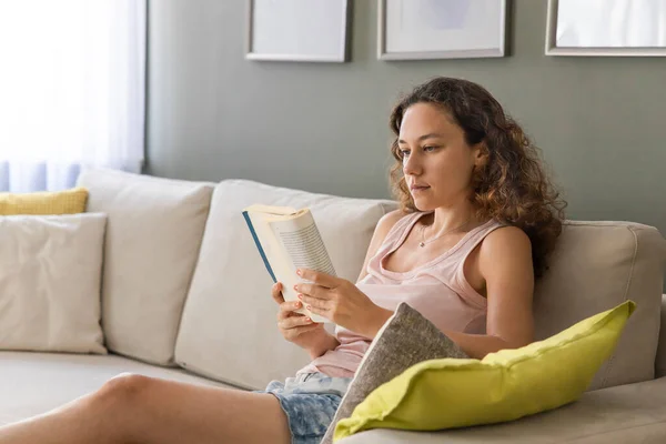 Young Woman Lying Sofa Reading Boo — Stockfoto