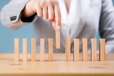 İş kadını tahta domino taşları yerleştiriyor. İş, risk yönetimi, çözüm, strateji ve yatırım kavramları