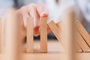 Parmak, düşmek üzere olan domino taşlarının zincirleme reaksiyonunu durduruyor. İş, risk yönetimi, çözüm, strateji ve yatırım kavramı