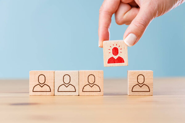 Person icon on wooden cube with hand picked different from the crowd