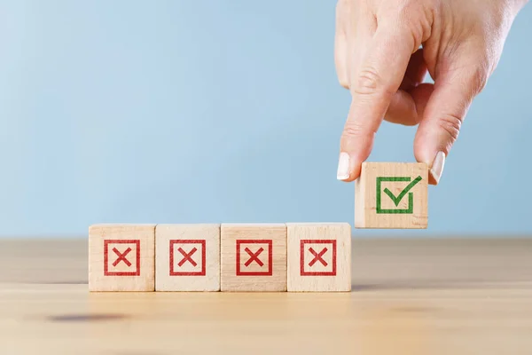 Woman hand selects checkbox with green checkmark from row of multiple boxes with red crosses. Right or Wrong. Concept of positive or negative decision making or choice of approval or rejection