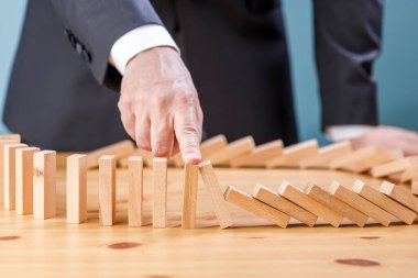 İşadamı, tahta bloğun risk kavramı ile domino hattına düşmesini engelliyor.