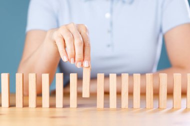 İş kadını tahta domino taşları yerleştiriyor. İş, risk yönetimi, çözüm, strateji ve yatırım kavramları