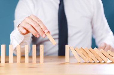İşadamı tahta domino taşları yerleştiriyor. İş, risk yönetimi, çözüm, strateji ve yatırım kavramları