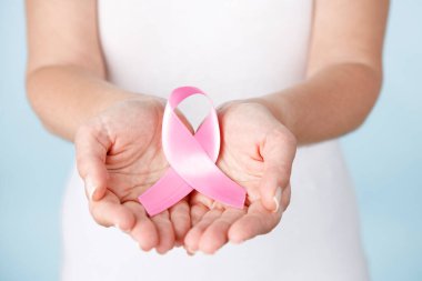 Kadın elleri pembe kurdele tutuyor. Göğüs kanseri farkındalığı.