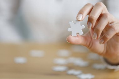 Tahta masada yapboz parçası gösteren bir kadın eli. Alzheimer hastalığı, hafıza kaybı ve akıl sağlığı konsepti için sağlık hizmetleri