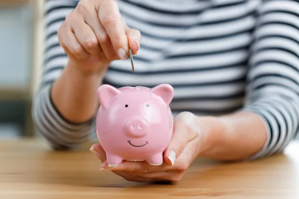 Woman putting money into piggy bank. Concept of money saving and budgeting. Saving money with pink cute piggy bank