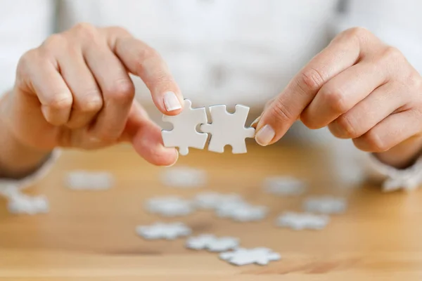 Woman\'s hand showing a jigsaw puzzle piece on wooden table. Healthcare for alzheimer disease, memory loss and mental health concept