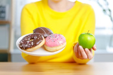 Çörek ve elma arasında seçim yapmak. Sağlıklı bir vücut için iyi bir besin.