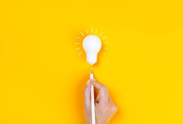 白いペンで電球を指す女性の手 黄色の背景にビジネス創造性とインスピレーションの概念 — ストック写真
