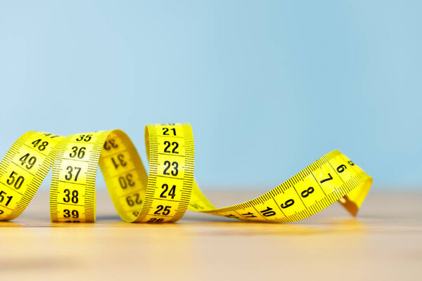 Желтая измерительная лента на деревянном столе
