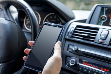 Adam araba sürerken cep telefonu kullanıyor.