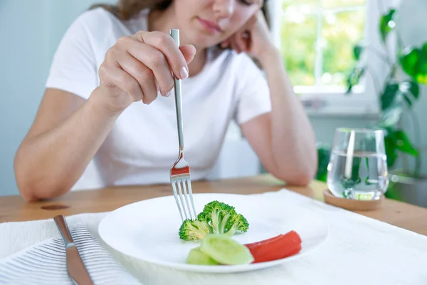 第一天的饮食 不快乐的年轻女人看着盘子里的小西兰花 — 图库照片