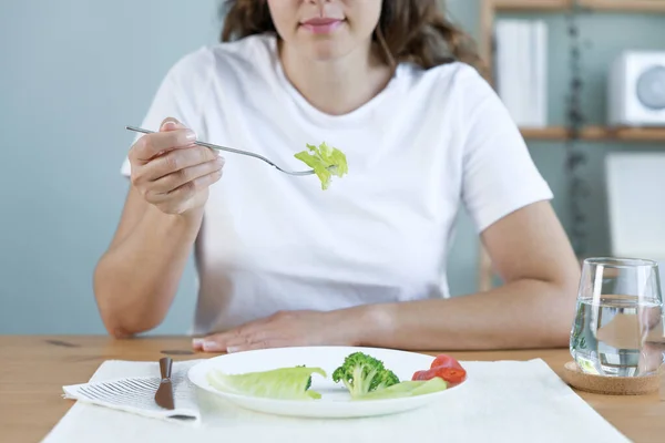 Dieting problems. Eating disorder. Young woman eating lettuc