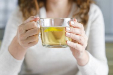 Bir fincan yeşil çay içen genç bir kadın. Evde dinlenme zamanı. Sağlıklı içecek.