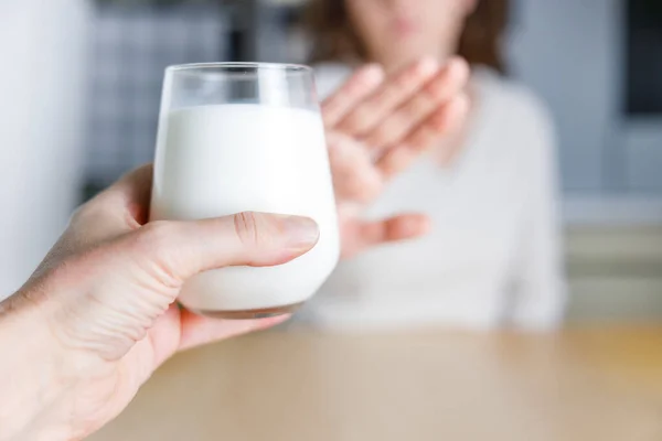Lactose intolerance. Young woman gesturing no to glass of mil