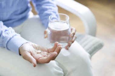 Kadın bir bardak suyla ilaç alıyor. İlaç hapları ve bir bardak su ile baş ağrısı. Etkili ilaçların günlük normu, vücut sağlığı danışmanları için modern eczane