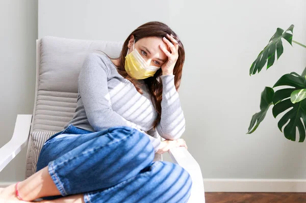 Young woman in medical mask staying at home under quarantin
