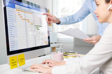 Gantt çizelgesini güncelleyen proje yönetimi ekibi, bilgisayarda planlama, ofiste iki iş adamı