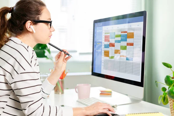 コンピュータ上のカレンダーを使用してフリーランスの女性は 時間管理を改善し イベント タスクや会議を効率的に計画し 生産性を向上させ 週日と労働時間を整理します — ストック写真