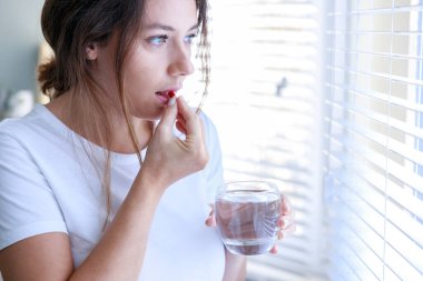 Elinde bir bardak suyla antibiyotik kullanan hasta bir kadın.