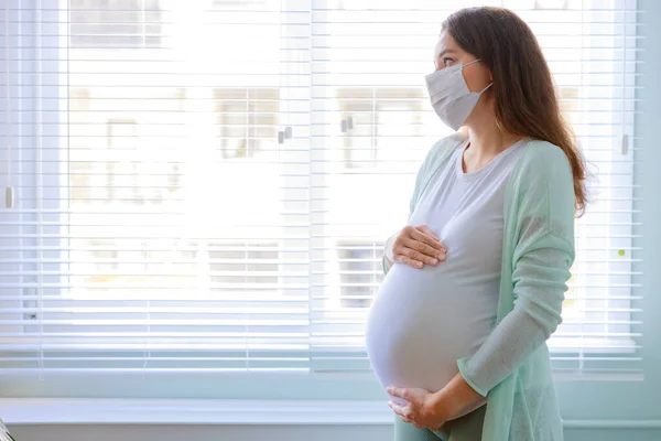自宅で隔離された医療マスクの若い妊婦 自宅でのコロナウイルスのパンデミック期間 — ストック写真