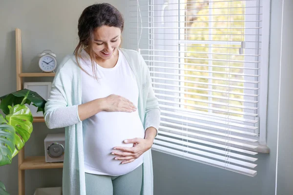 Mutlu Hamile Kadın Hamile Karnına Dokunuyor Pencerenin Kenarında Duruyor — Stok fotoğraf