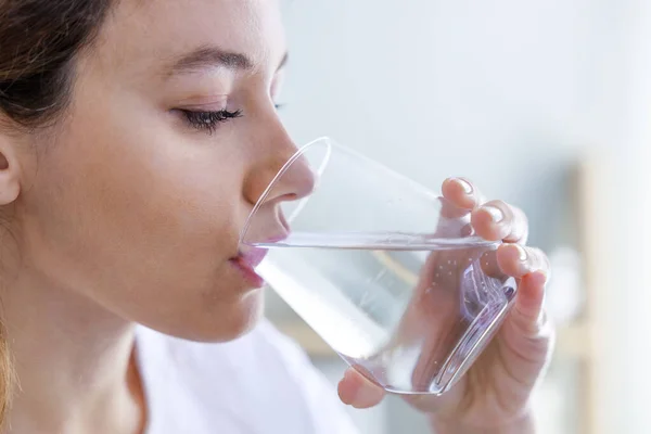 若い女性は家で水を飲む 十分な水の概念を飲むことの健康上の利点 — ストック写真