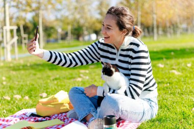 Mutlu genç kadın ve kedisi baharda bir parkta