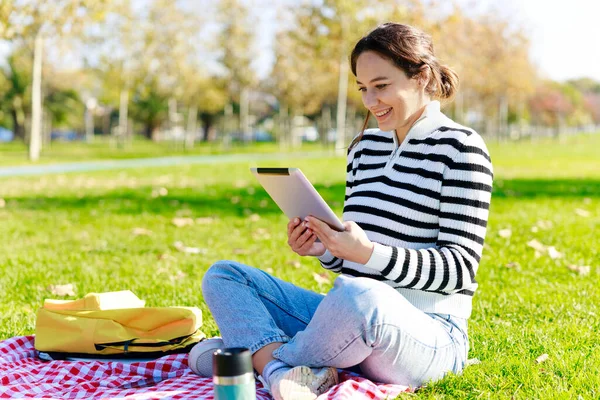 Νεαρή Γυναίκα Που Χρησιμοποιεί Tablet Κάθεται Στο Πάρκο — Φωτογραφία Αρχείου